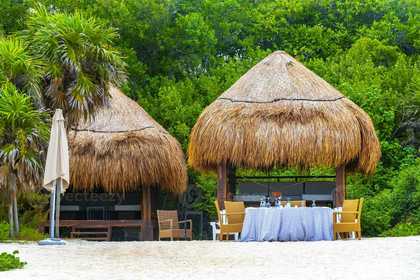Palapa thatched roofs palms parasols sun loungers beach resort Mexico. photo