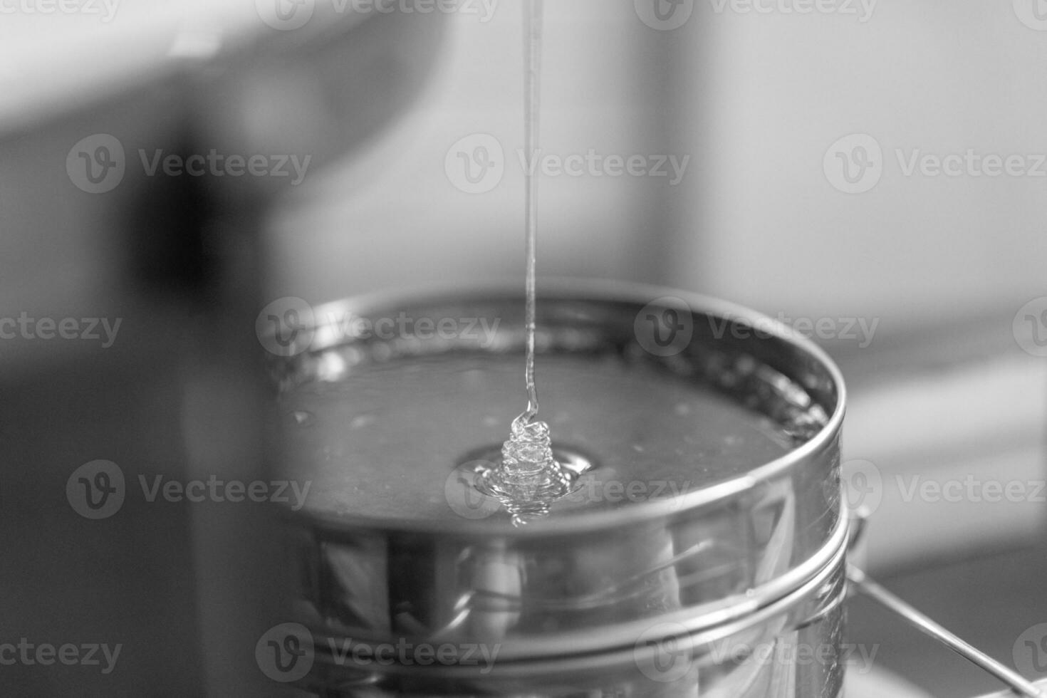 Drop of bee honey drip from hexagonal honeycombs photo