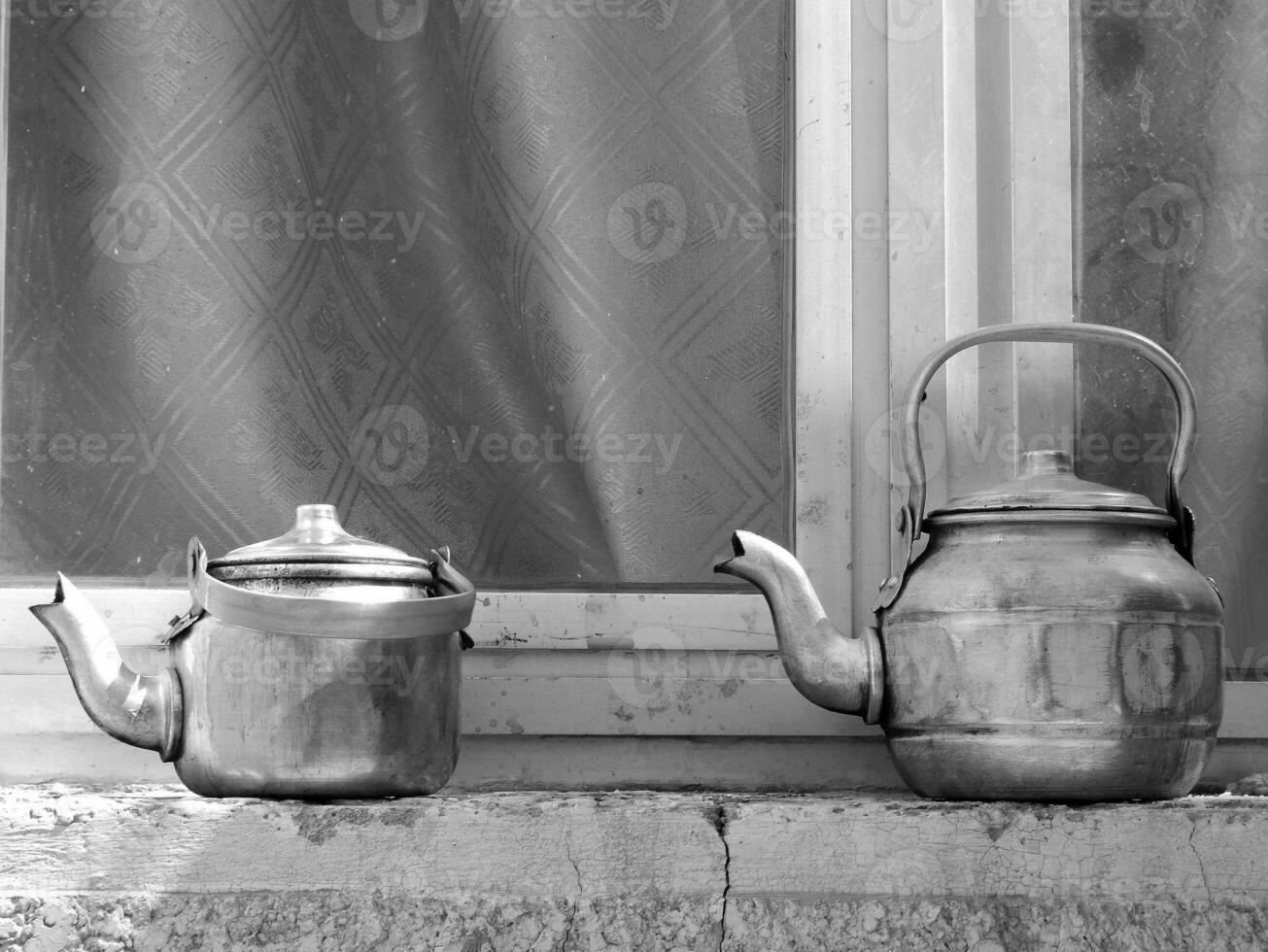 Copper teapots standing to concrete sill, kettles on street shop window before glass photo