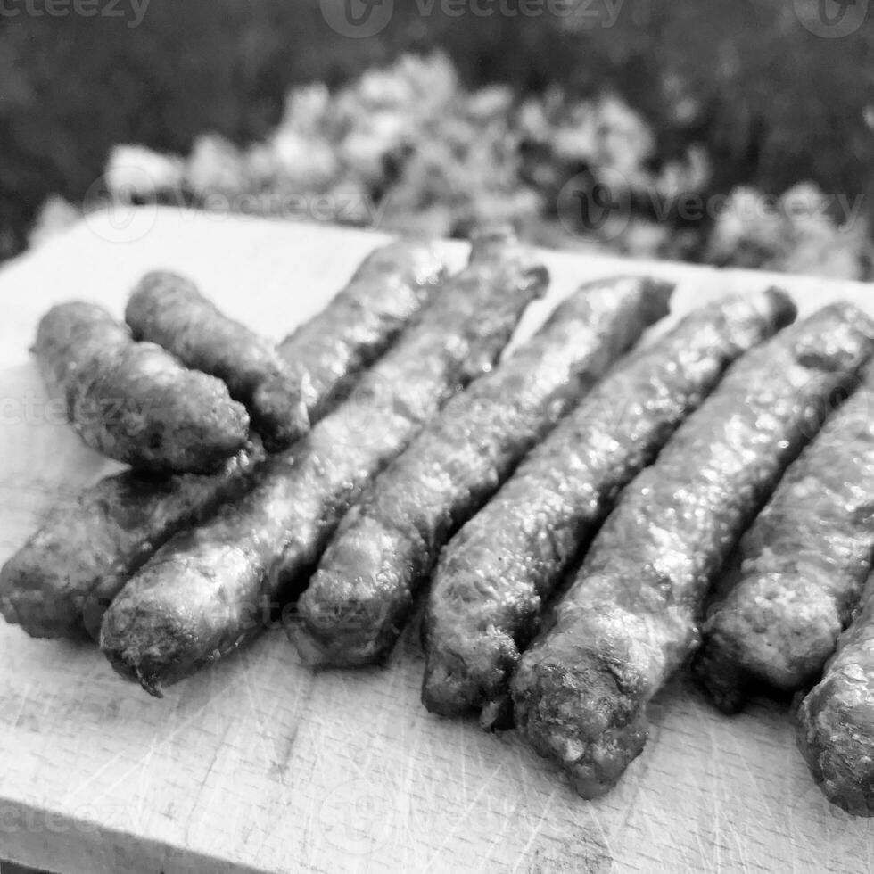 Barbecue with fiery Bavarian sausages on grill in garden outdoors photo