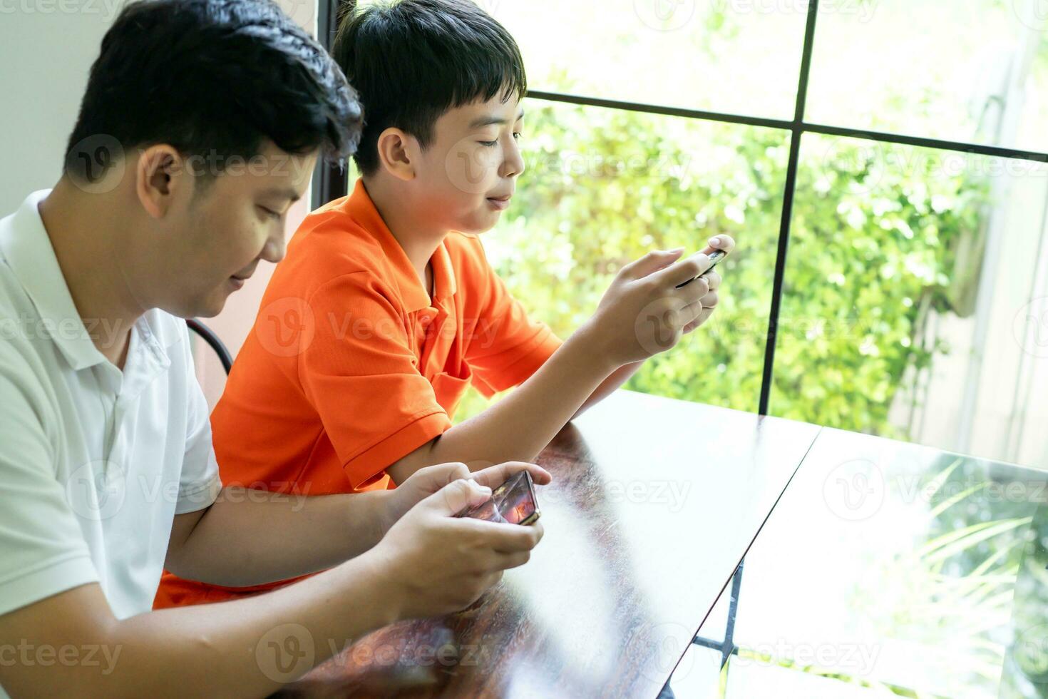 Asian father and son with mobile phone playing games together dad spend time with children family. photo