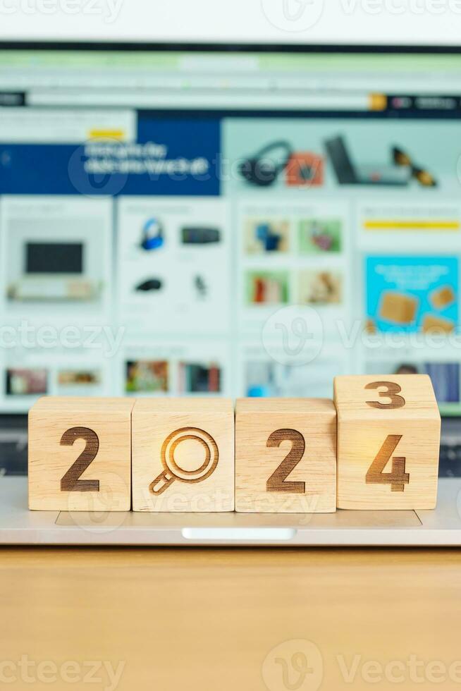 2024 block with magnifying glass icon against laptop background. Hiring, recruitment, job, jobless SEO, Search Engine Optimization and New Year concepts photo