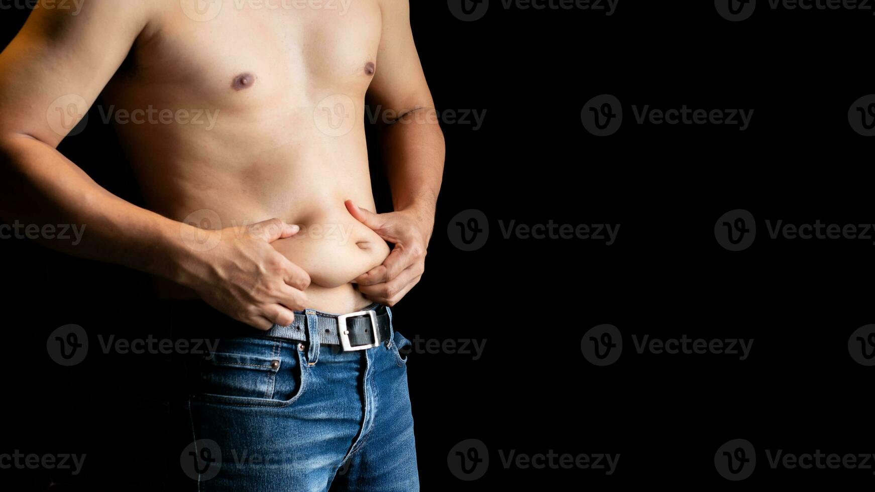 Body care concept  Shirtless man and hand pinching him excess belly fat, Fat unhealthy men cellulite  body isolated on black background photo