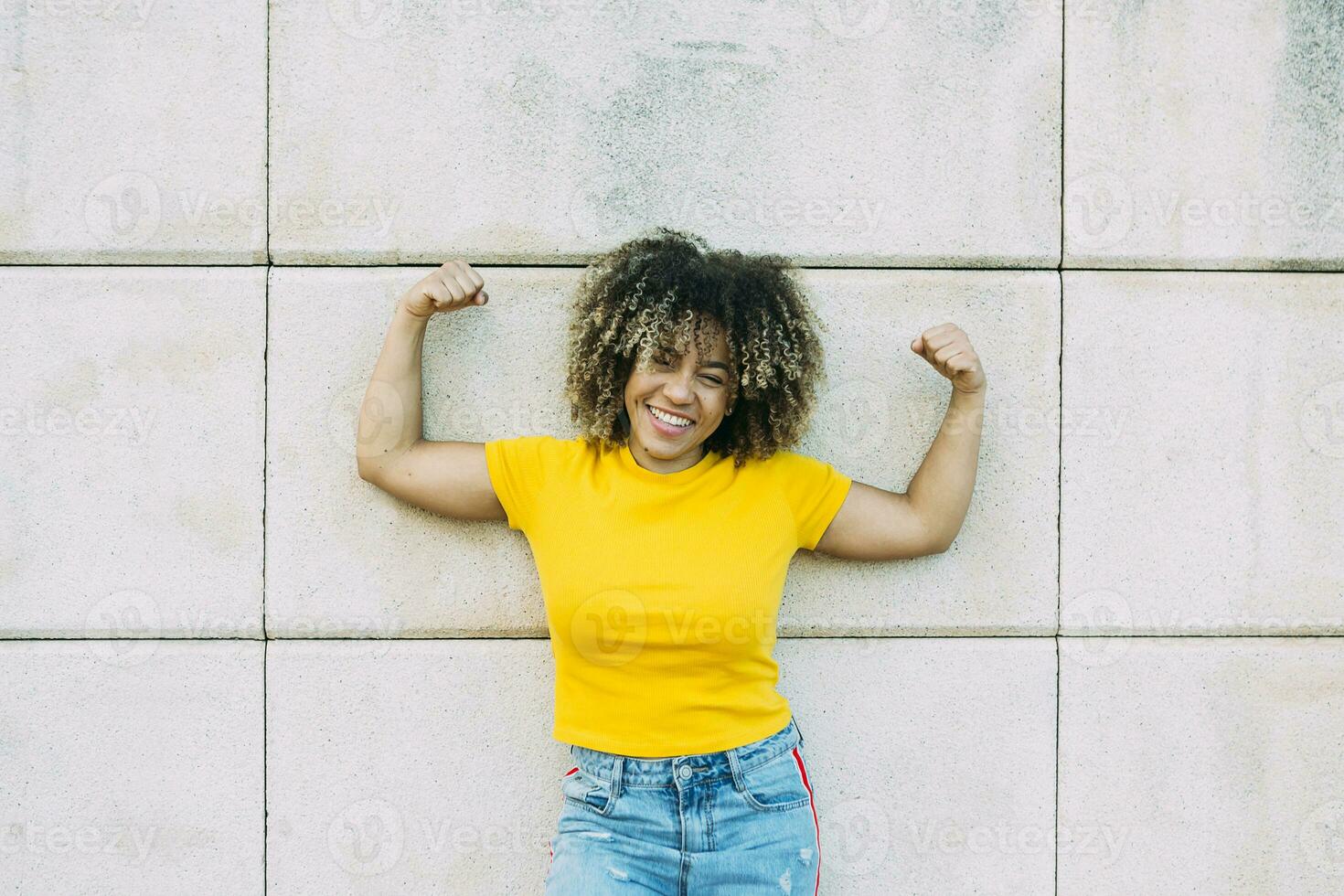 Portrait of smiling strong woman on wall photo