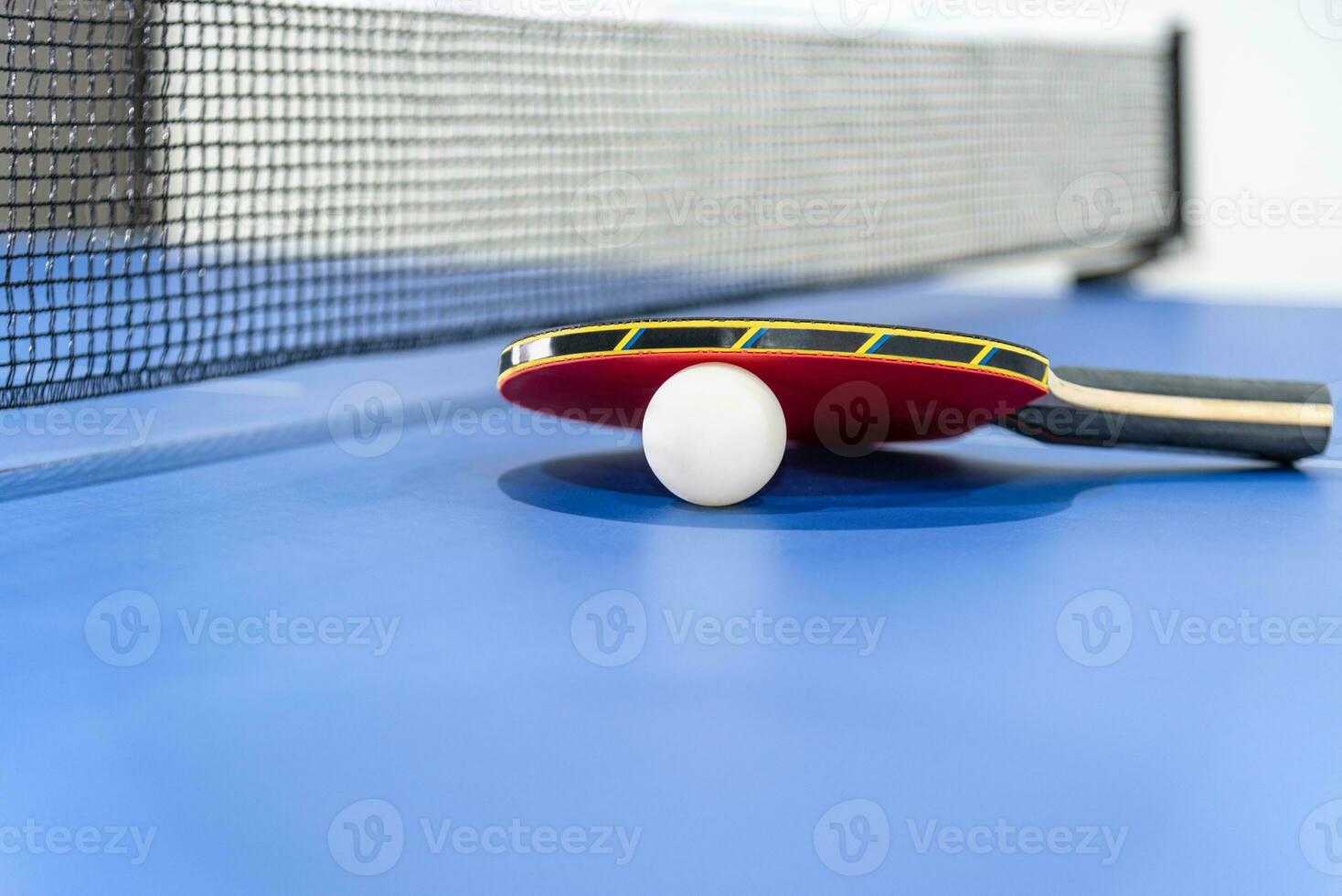 Closeup red table tennis paddle white ball and a net photo