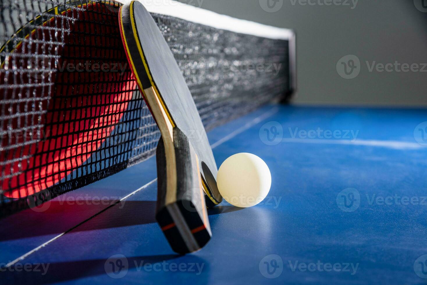 Closeup red table tennis paddle white ball and a net photo
