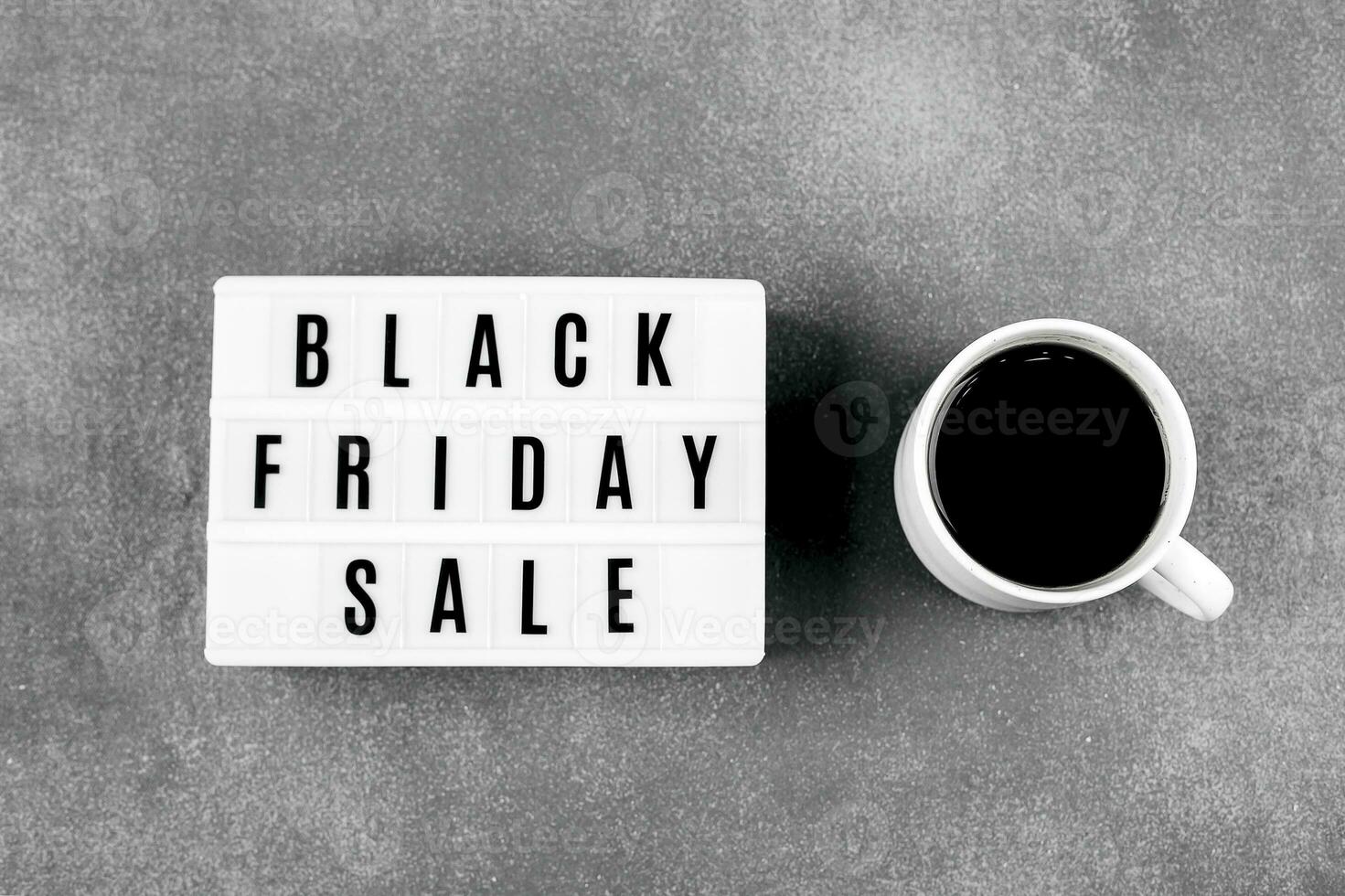 Black friday sale word on lightbox and cup of coffee on red background table. Flat lay, top view photo