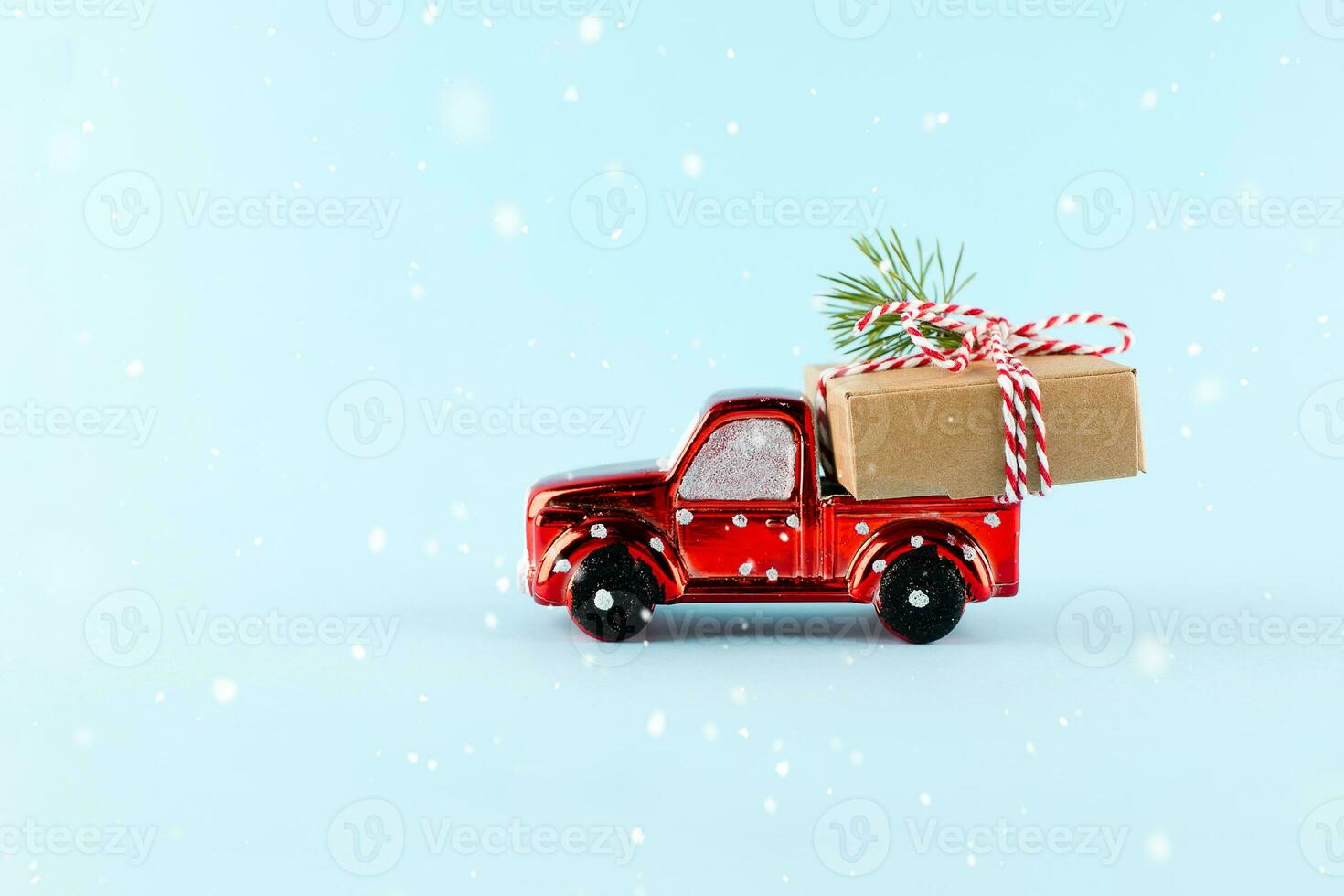 Red toy car delivering Christmas or New Year gift present box on blue background. photo