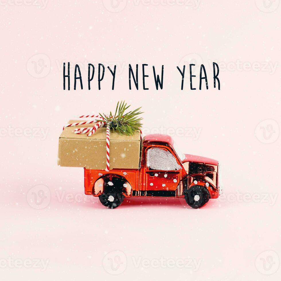 Red toy car delivering Christmas or New Year gift present box on pink background. photo