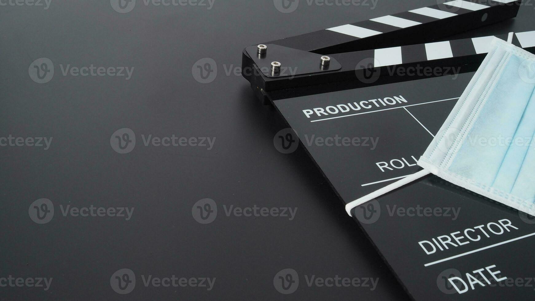 Black Clapper board or movie slate with face mask on black background. photo