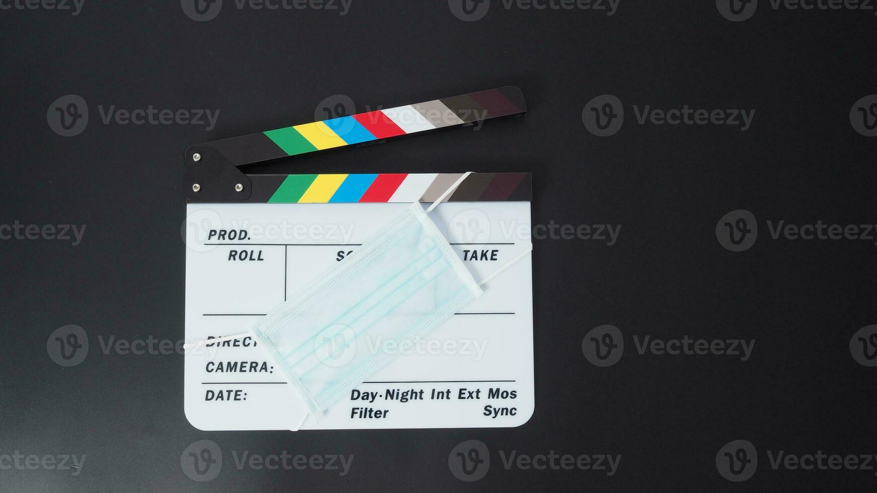 Clapper board or movie slate with face mask. it use in video production and cinema industry on black background. photo