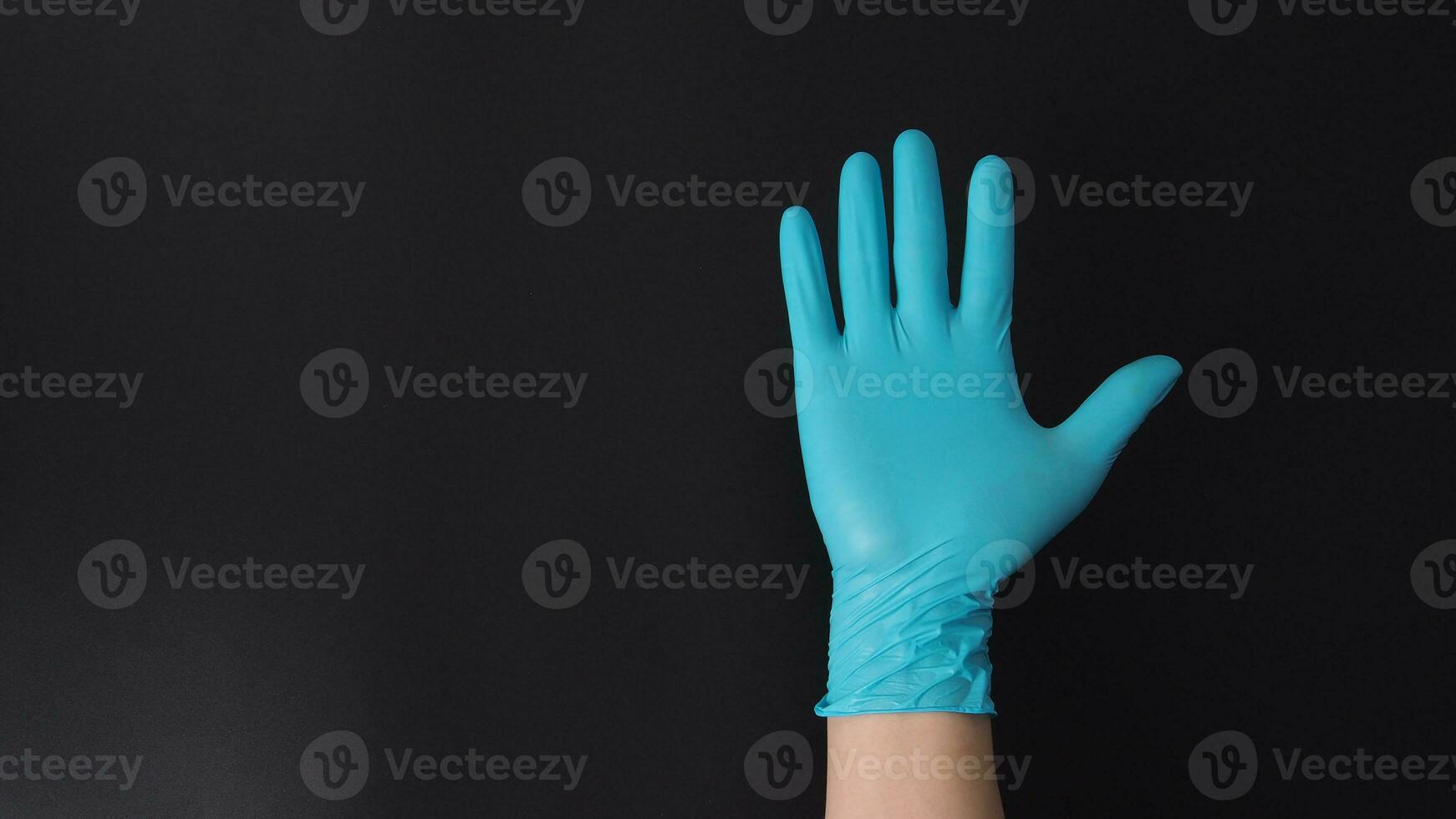 mano vistiendo azul médico guantes haciendo cinco dedos número en negro antecedentes. foto