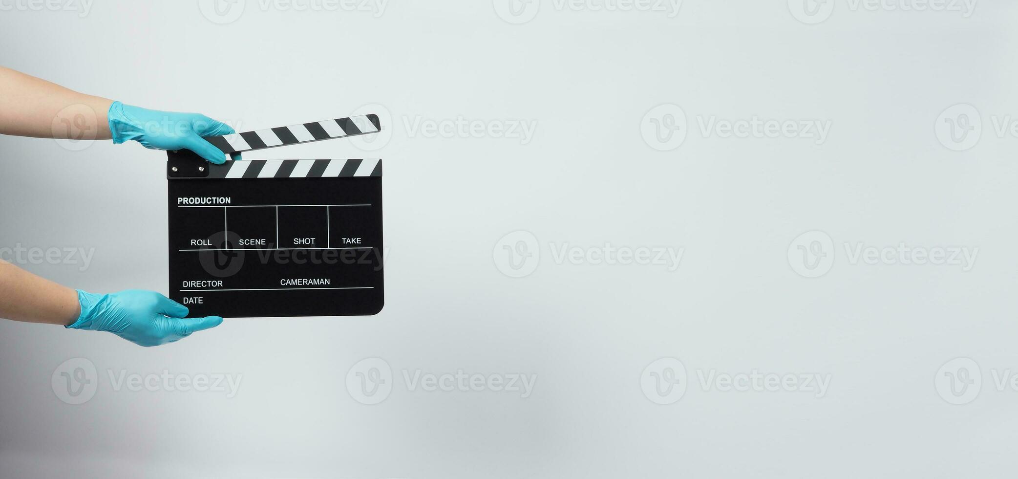 Hand is wear gloves and hold black Clapper board or movie slate. it use in video production and cinema industry on white background. photo