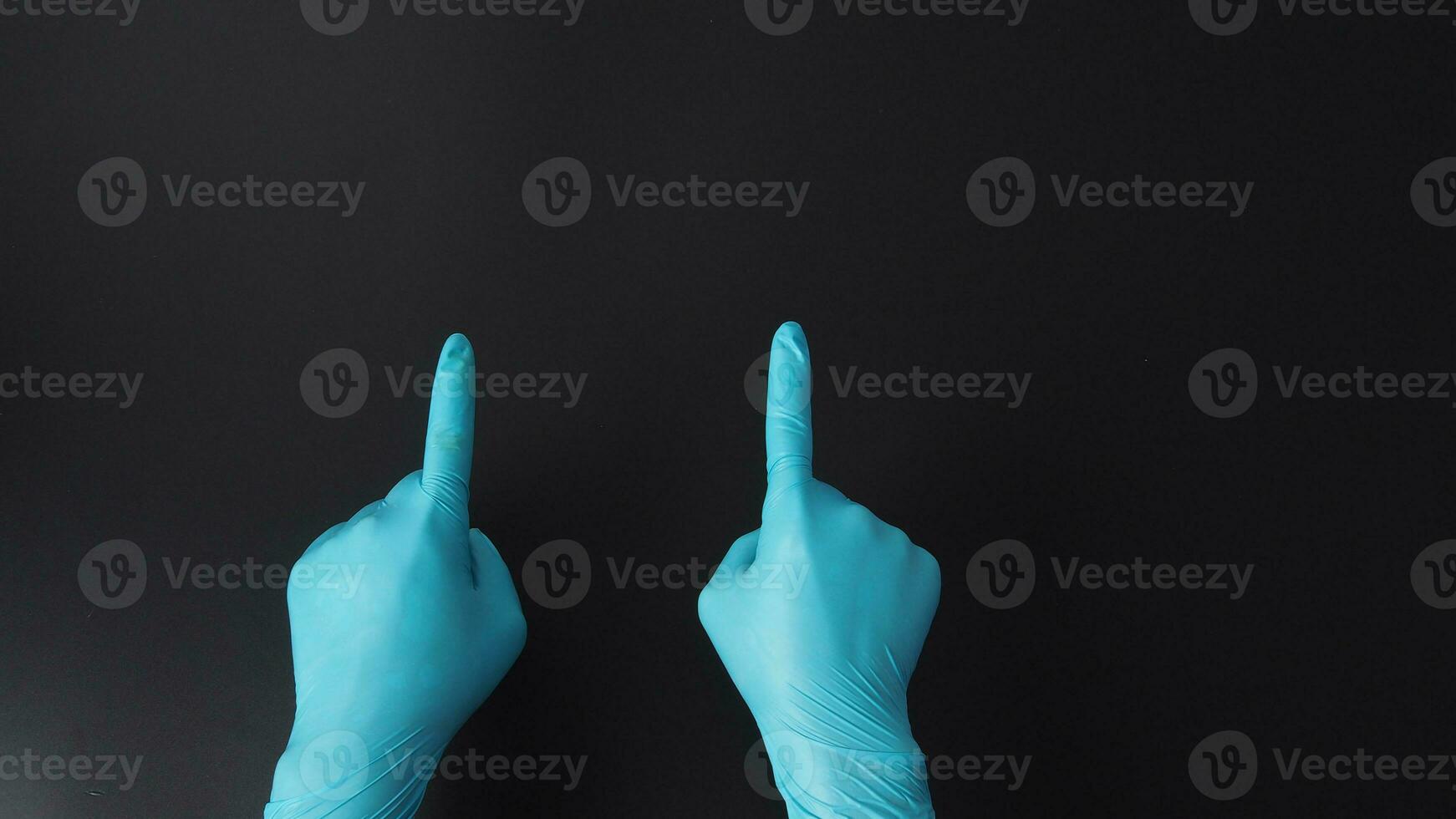 Two hand is wear blue doctor gloves and point the finger on black background. photo