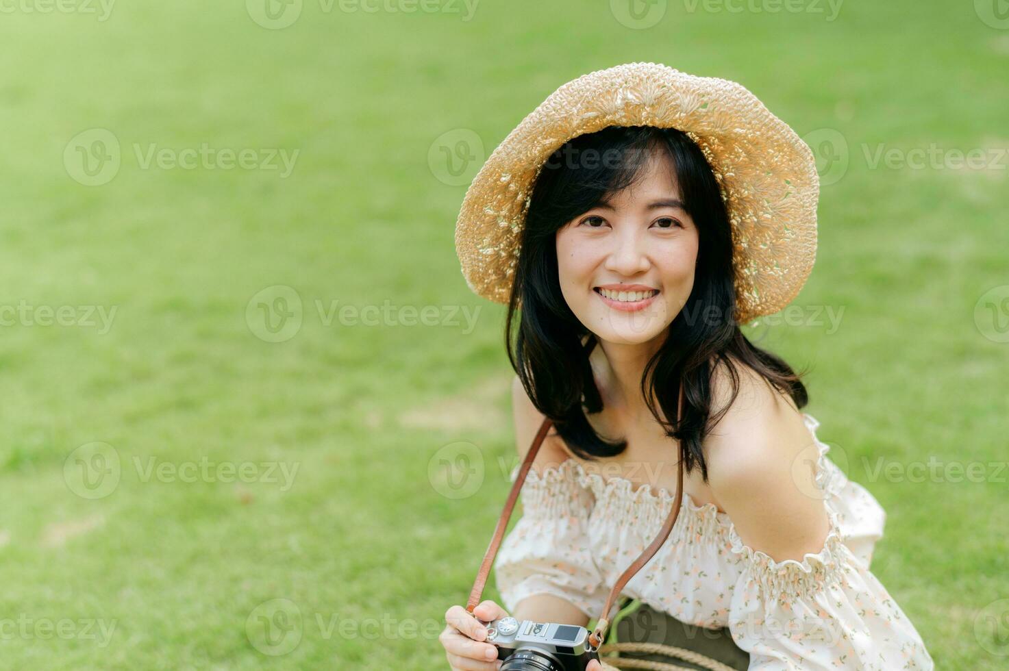 Portrait of asian young woman traveler with weaving hat and basket and a camera on green public park nature background. Journey trip lifestyle, world travel explorer or Asia summer tourism concept. photo