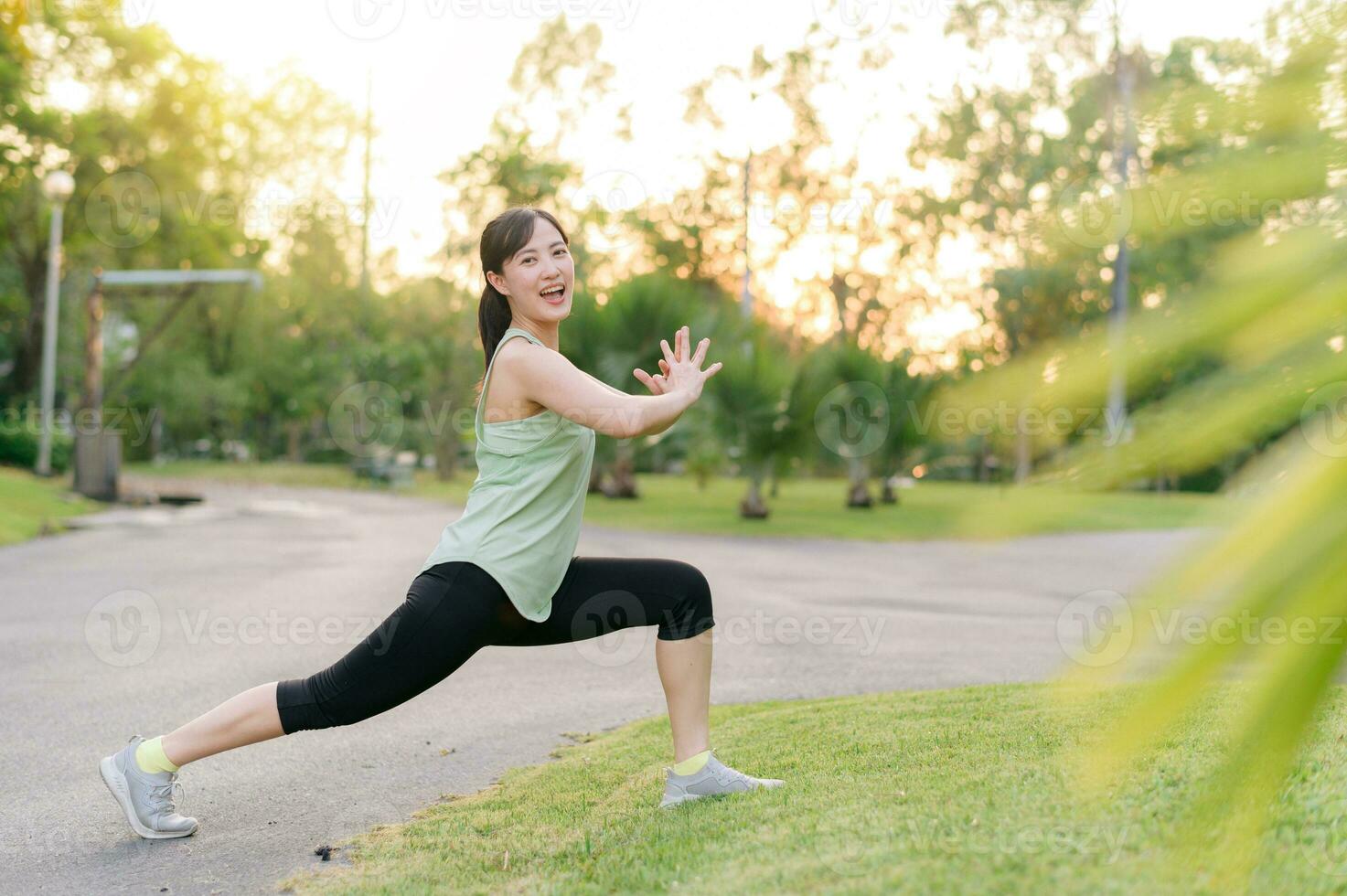 hembra persona que practica jogging. ajuste joven asiático mujer con verde ropa de deporte extensión músculo en parque antes de corriendo y disfrutando un sano exterior. aptitud corredor niña en público parque. bienestar siendo concepto foto