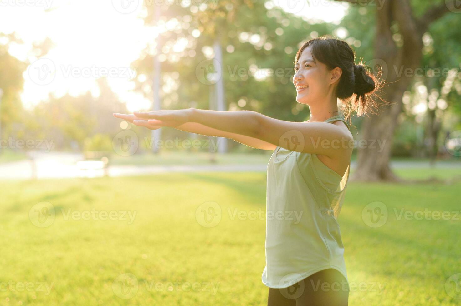 Female jogger. Fit young Asian woman with green sportswear stretching muscle in park before running and enjoying a healthy outdoor. Fitness runner girl in public park. Wellness being concept photo