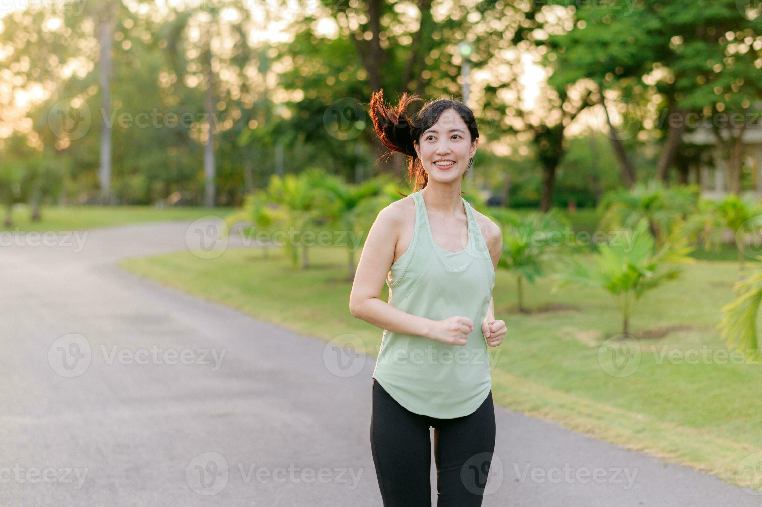 Sport Fitness Woman Running In Park On Summer Day. Asian Female Runner  During Outdoor Workout. Fit Sport Fitness Model Of Mixed Asian / Caucasian  Ethnicity. Stock Photo, Picture and Royalty Free Image.