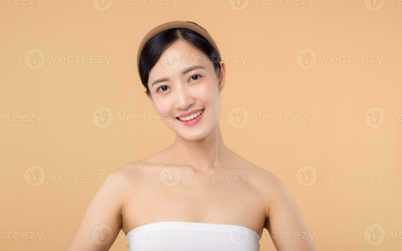 beauty asian young woman model with fresh glowing hydrated facial skin. girl person with natural makeup and healthy skin portrait isolated on beige studio background. spa treatment, skin care concept. photo