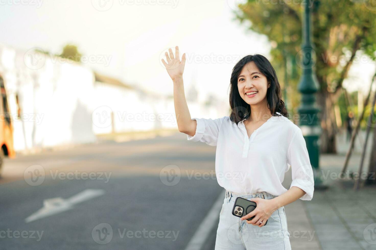 retrato joven hermosa asiático mujer ondulación mano a amigo por el calle en soleado día festivo. foto