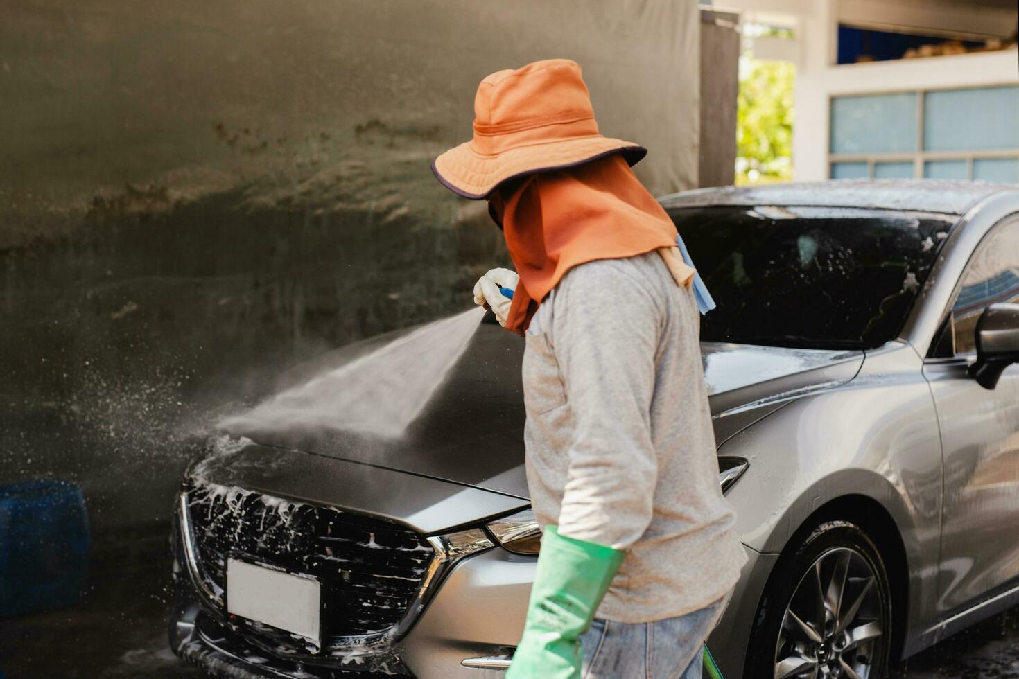 Unidentified man washing car on carwash station using high pressure water. photo