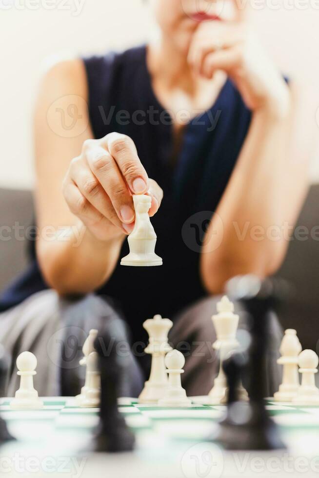 Woman playing chess board game at home. photo