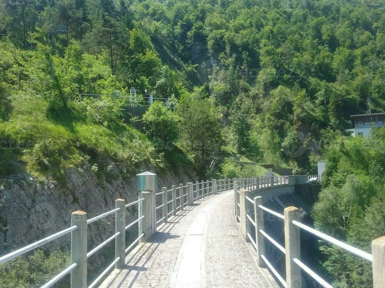 A metal pedestrian bridge below the hydroelectric dam photo