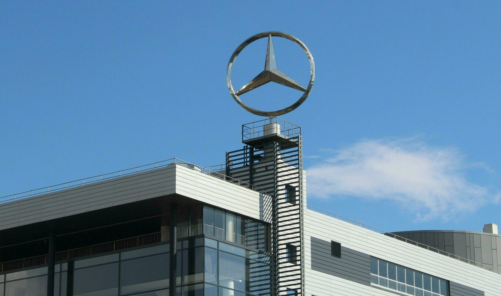 Large Mercedes-Benz Logo. Sankt Petersburg Russia - 10 03 2023 A tall Mercedes-Benz sign with the recognizable brand emblem stands above the trees at a dealership outside of St. Petersburg Russia photo