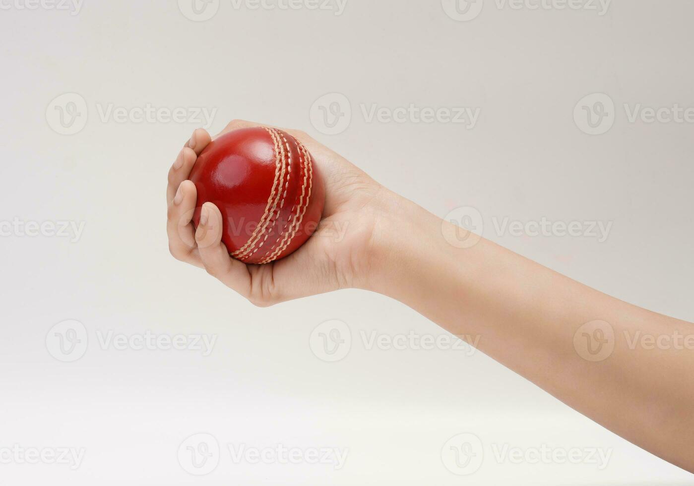 A Female Hand Holding A Red Test Match Leather Stitch Cricket Ball Closeup Picture White Background photo