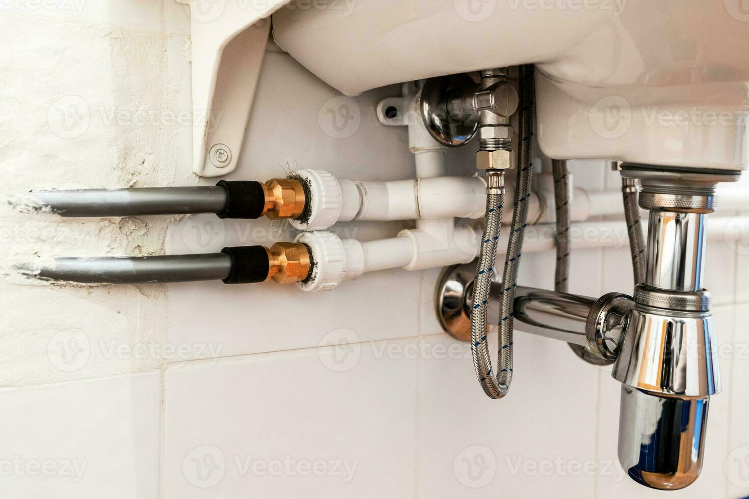 connection of various pipes under sink in bathroom photo