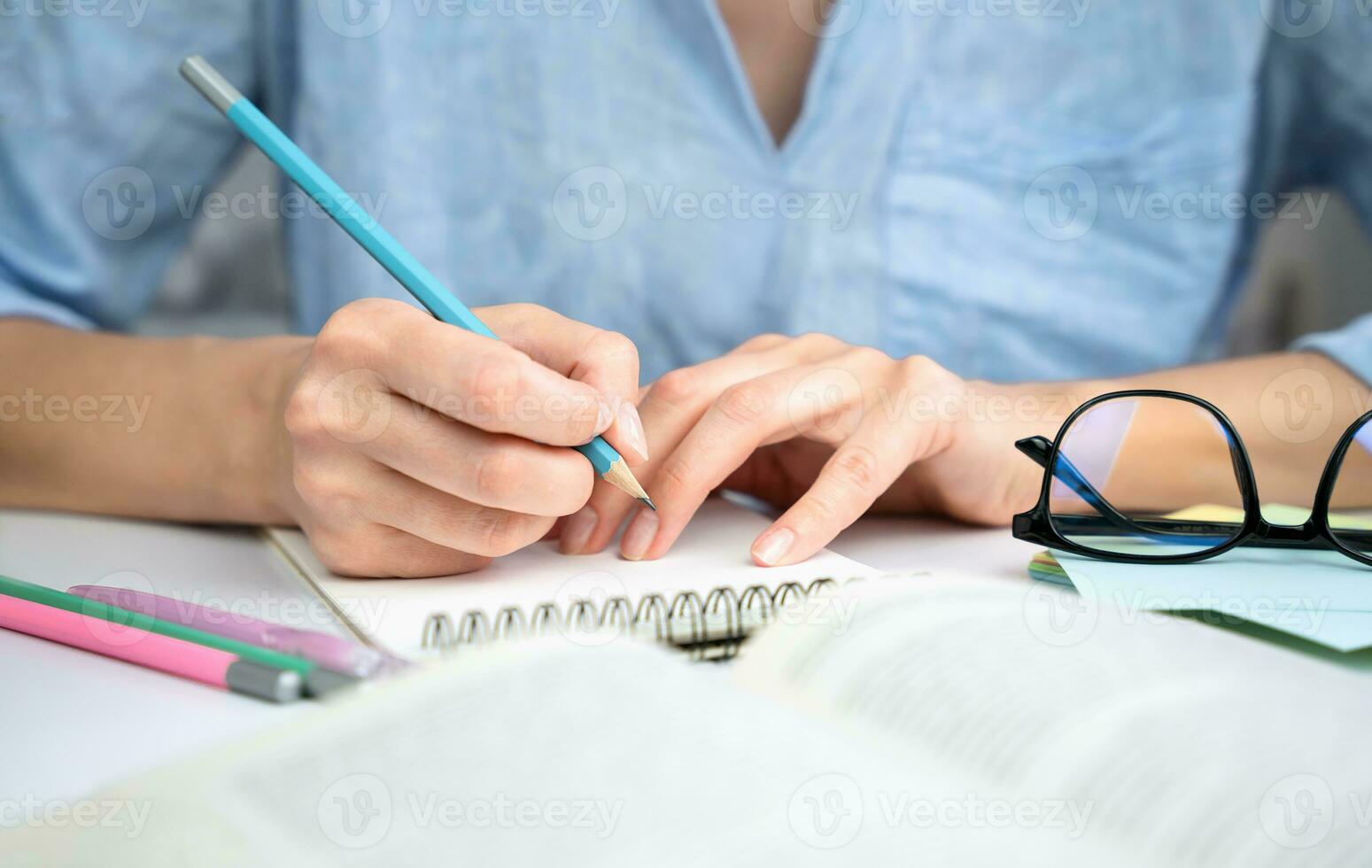 Girl student is preparing for the exam and takes notes in a notebook. Close-up. Selective focus. photo