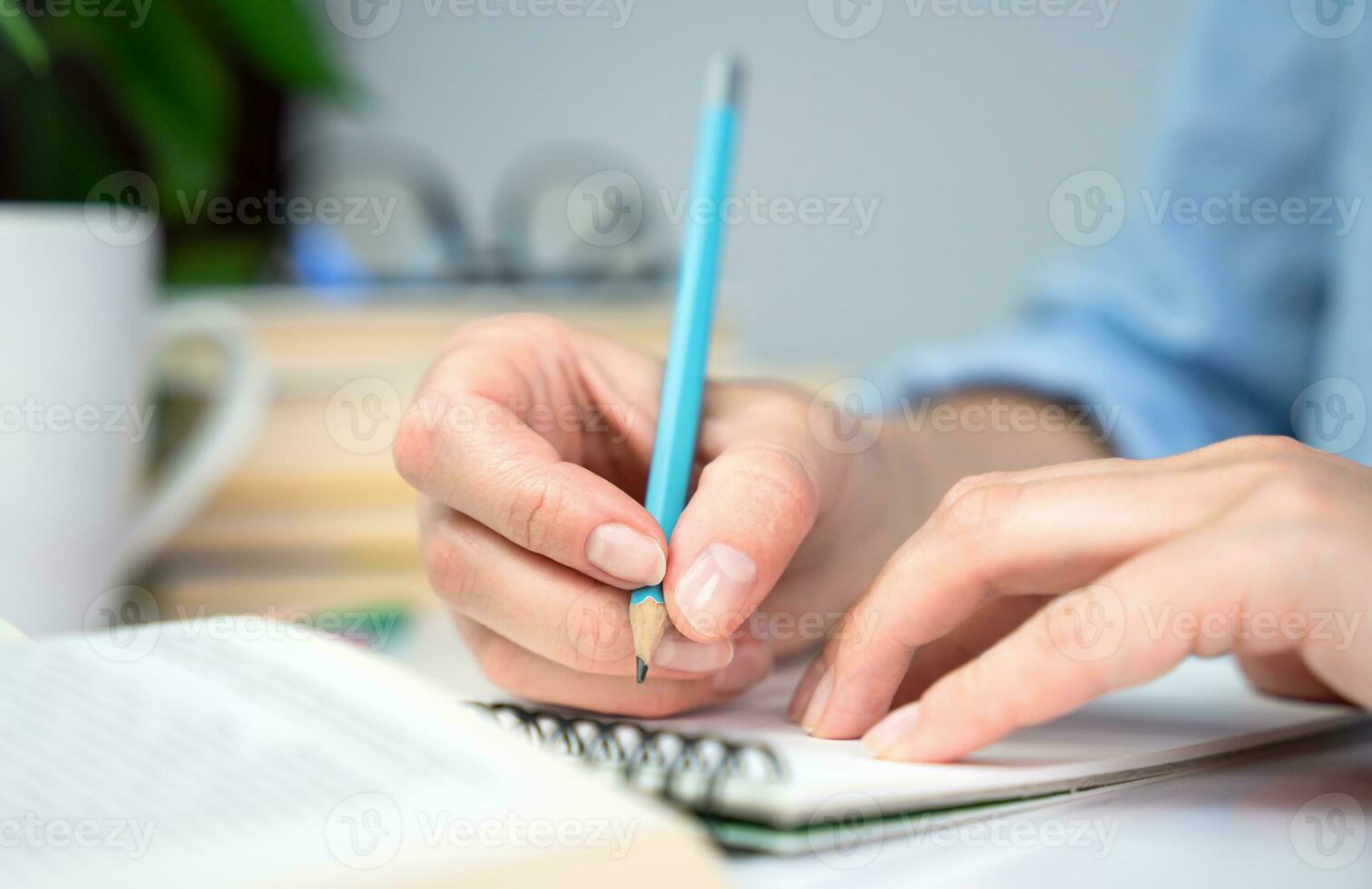 A young girl student prepares her homework and writes notes in a notebook. Close-up. Selective focus. photo