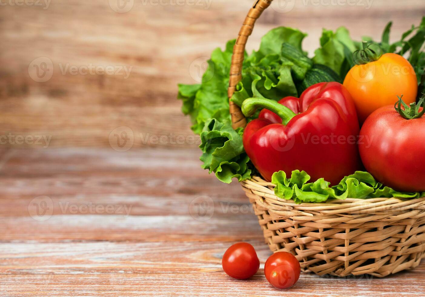 Fresh vegetables and greens in a wicker basket on a wooden background. Harvesting. Thanksgiving Day. Copy space. photo