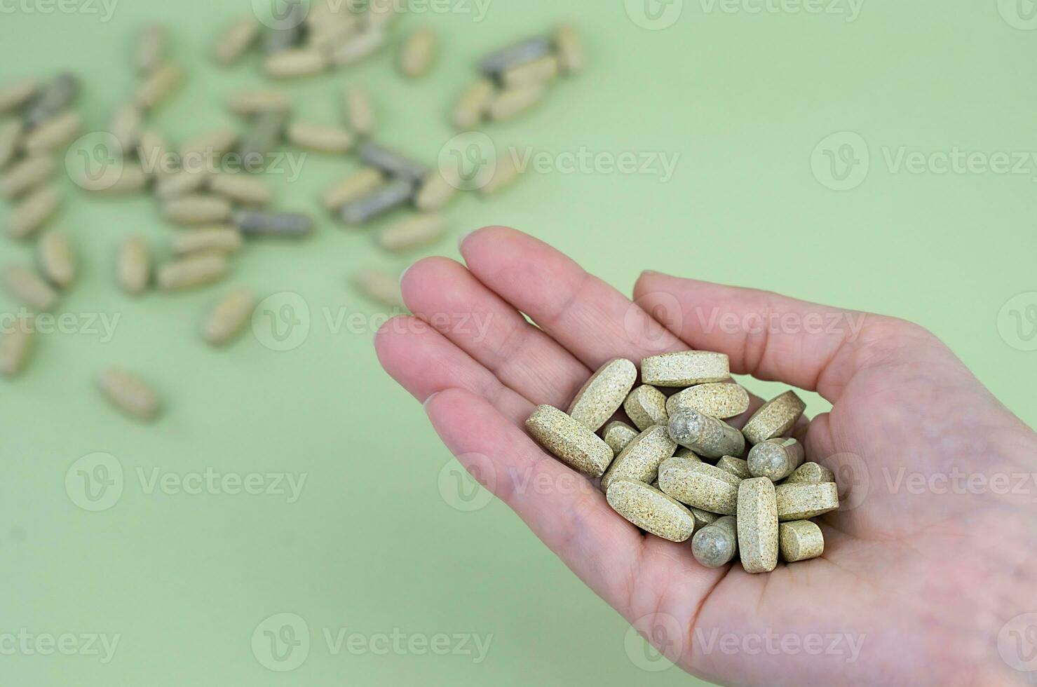 A woman's hand holds a handful of green pills. Fitness, sport and healthy lifestyle concept. Close-up. Top view. Copy space. photo