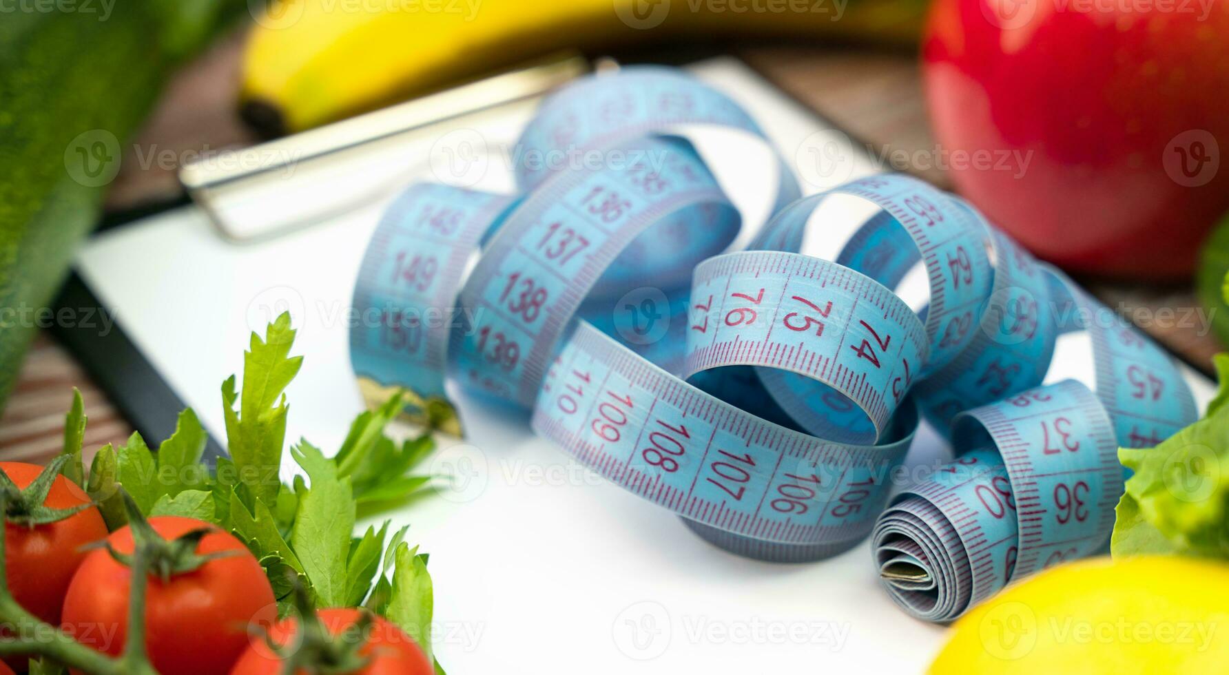 Measuring tape on blank notepad and healthy food on the table. Healthy food concept. Close-up. photo