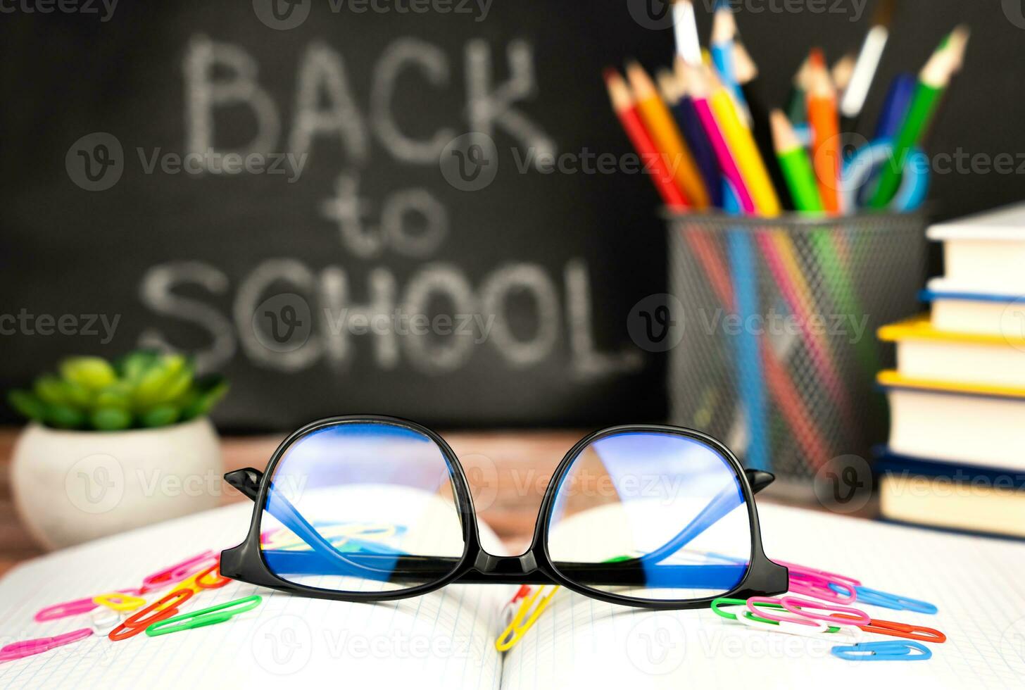 Holiday concept for Teacher's Day. Glasses, school supplies and a blackboard in the background with the words Back to school. Close-up. Selective focus. photo