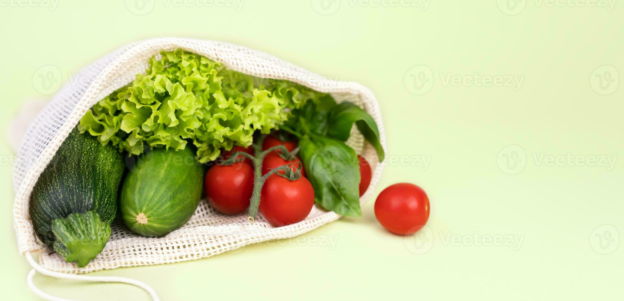 Eco bag with fresh vegetables on a green background. Zero waste concept. Copy space. Selective focus. photo