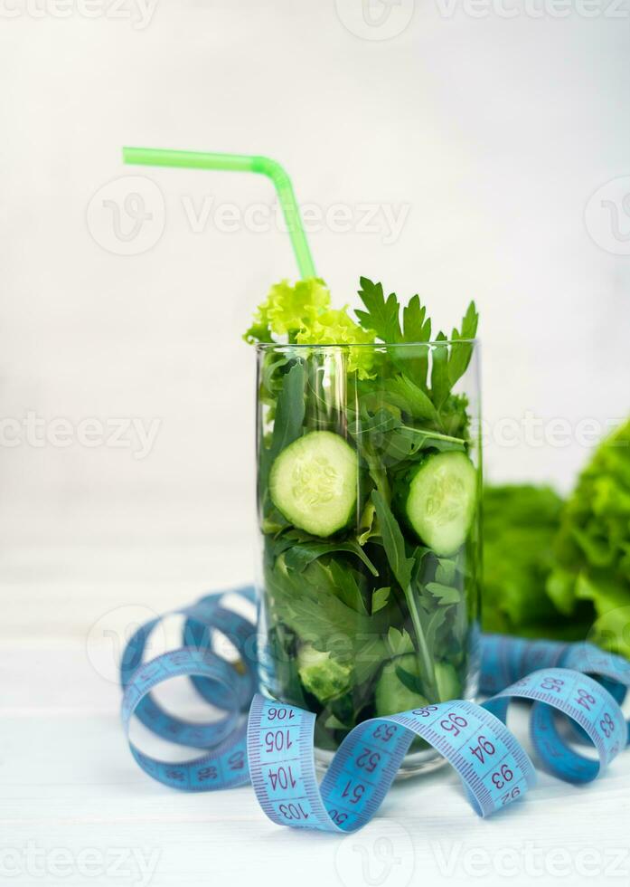 Ingredients for a healthy green smoothie in the glass and measuring tape on the table. Detox drink concept. Healthy food. photo