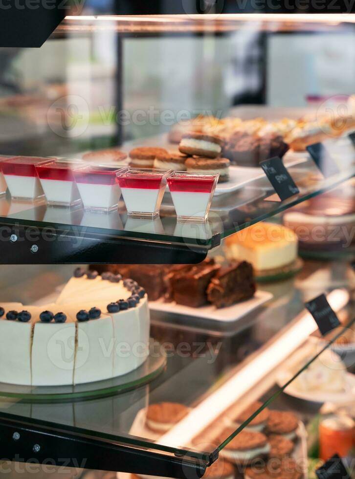 Delicious variety of cakes and pastries in a glass display case in cafe. Selective focus. photo