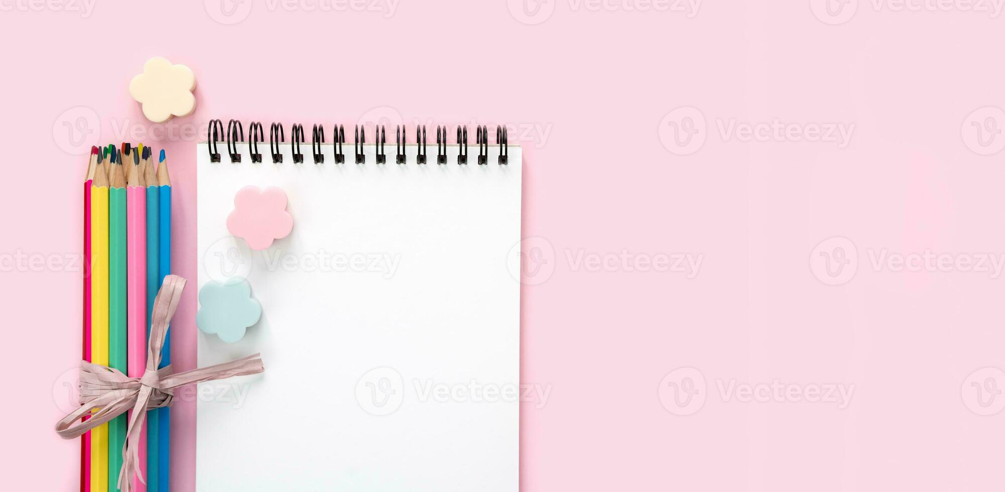 Blank notepad and colored pencils on a pink background. Back to school. Flatlay. Mockup. Top view. Copy space. photo