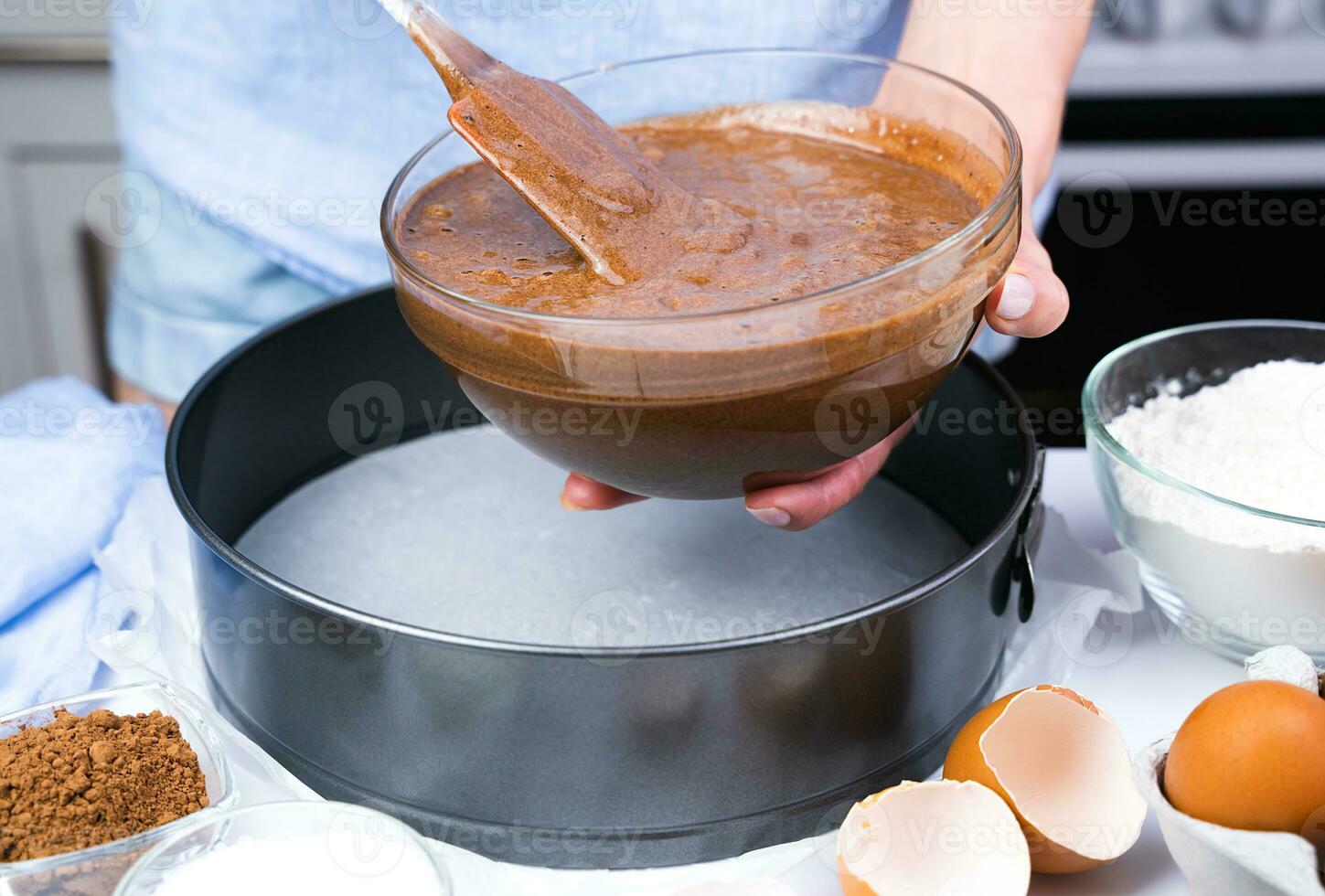 A young woman pours chocolate dough into a form. The process of making chocolate cake. Close-up. Selective focus. photo