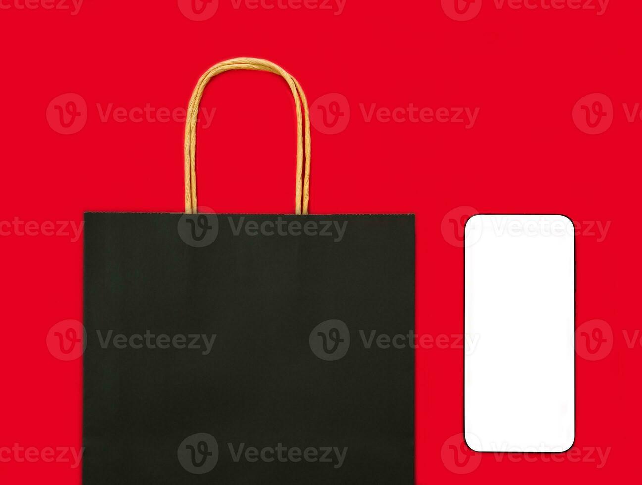 Shopping black bag and smartphone with a blank white screen on the red background. Mock up screen. Flatlay. Top view. Flatlay. Copy space. photo