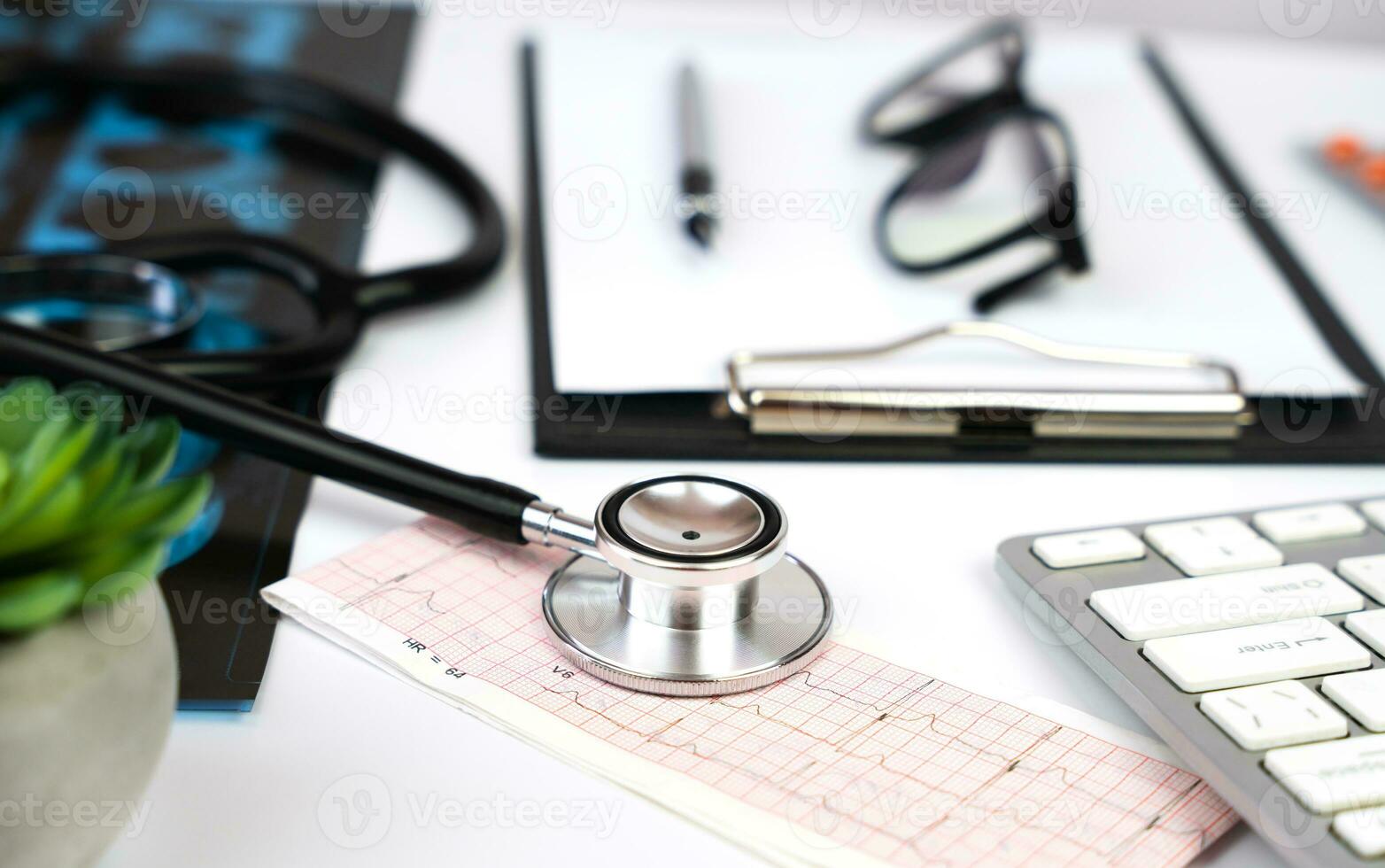 Medical stethoscope, blank clipboard, CT scan, cardiogram and glasses on the table. Doctor's workplace. Medical concept. Close-up. Selective focus. photo