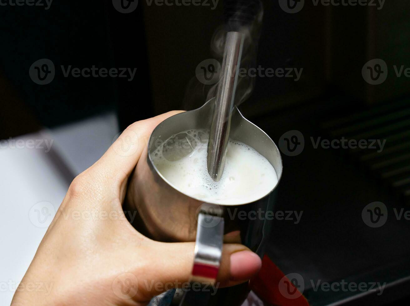 Barista girl froths milk on a coffee machine for making cappuccino or latte. The concept of making drinks from natural coffee. Close-up. Selective focus. photo