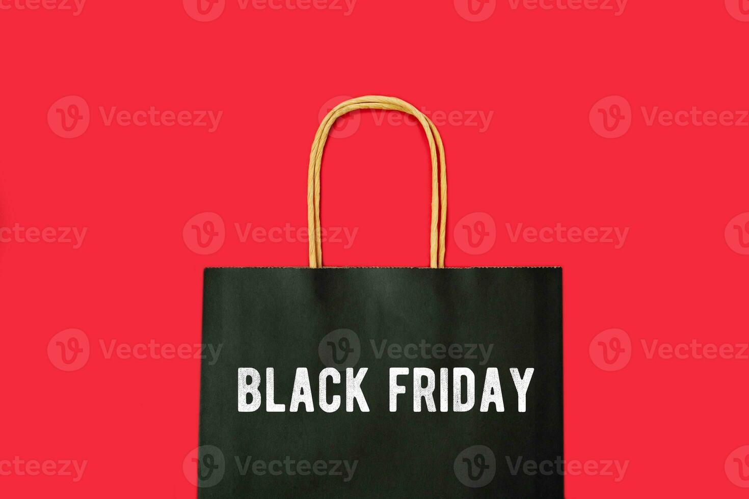 Paper black shopping bag with inscription Black Friday on the red background. Autumn sale. Promotional concept. Copy space. photo