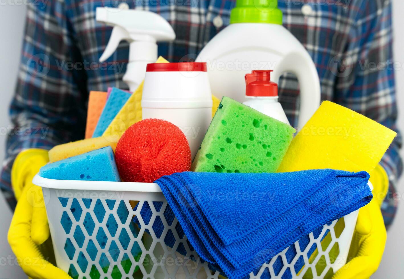 A young man in yellow rubber gloves holds cleaners and detergents. Spring cleaning in the house. Close-up. Selective focus. photo