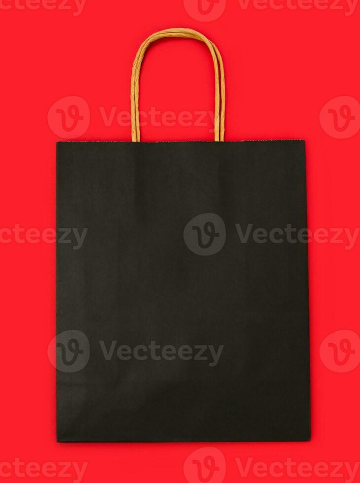 Paper black shopping bag mockup on the red background. Copy space. photo