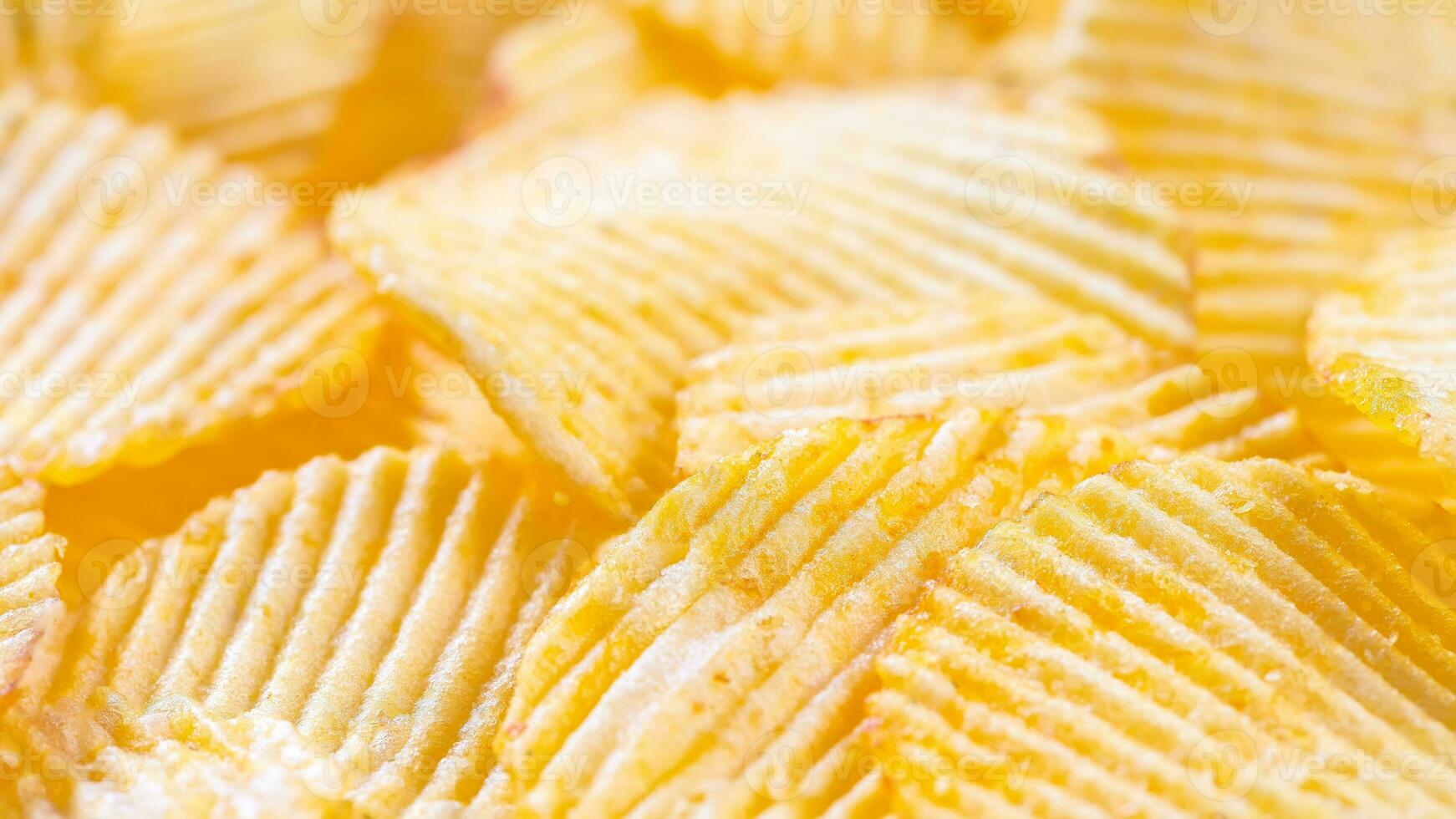 Yellow crispy ridged potato chips close up. Food background photo