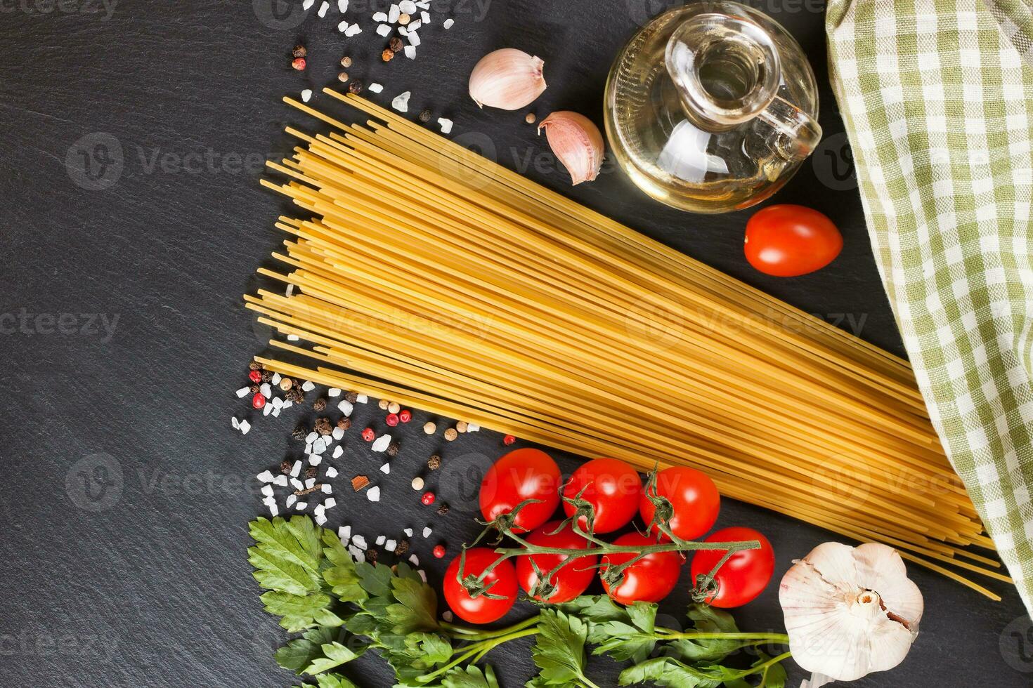 Pasta and cooking ingredients on black slate background. photo