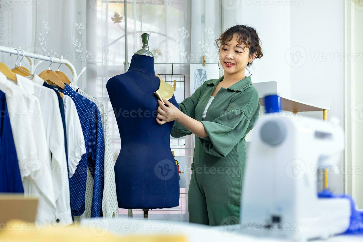 Fashionable freelance dressmaker is pinning her marking collar for new dress by pinning to mannequin while working in her artistic workshop studio for fashion design and clothing business industry photo